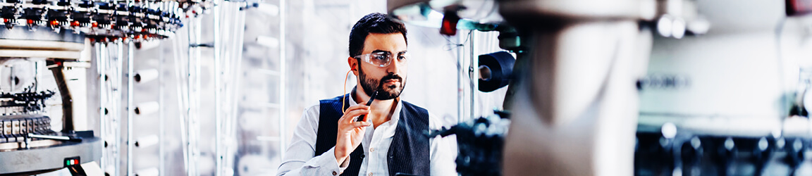 A worker with protective eyewear examines the subject of his work