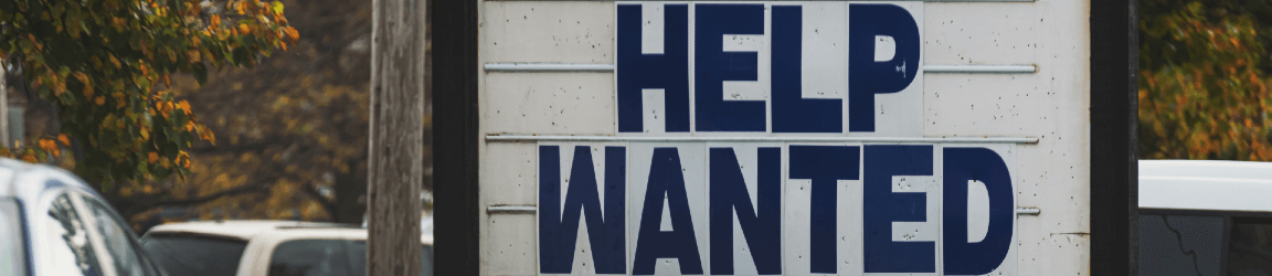 A roadside sign reads "Help Wanted"