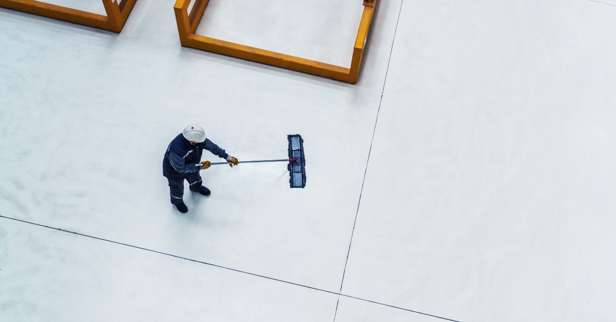 Custodian cleaning a commercial floor as part of janitorial and facilities maintenance work.