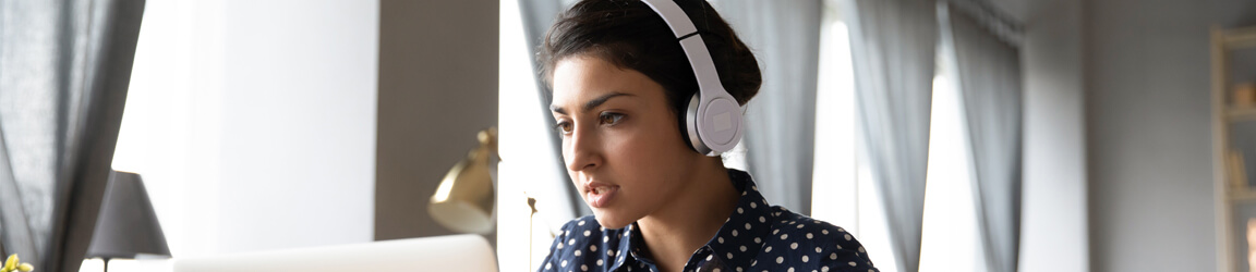 une femme portant un casque d’écoute qui regarde un ordinateur