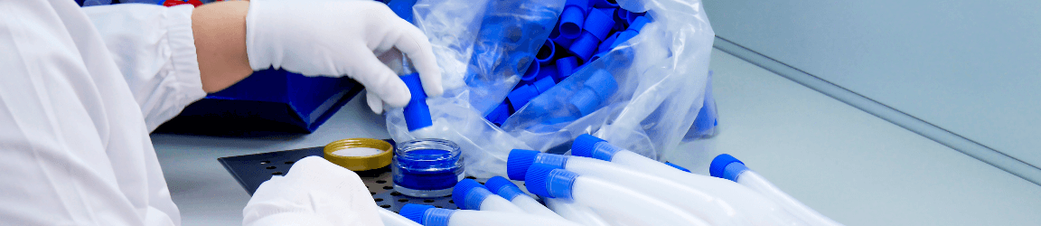 Une travailleuse de dispositifs médicaux portant des gants protectifs et une blouse de laboratoire construit un appareil  de respiration artificielle à son poste.