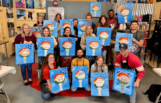 Men and women Aston Carter employees posing after a group painting activity.