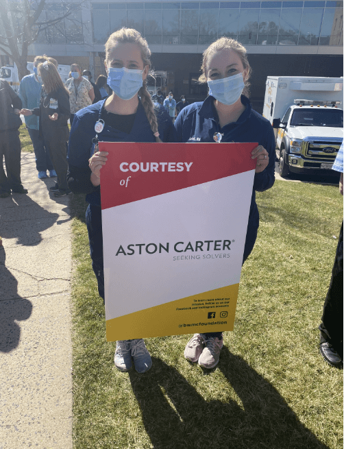 Des infirmières tenant une pancarte Aston Carter.