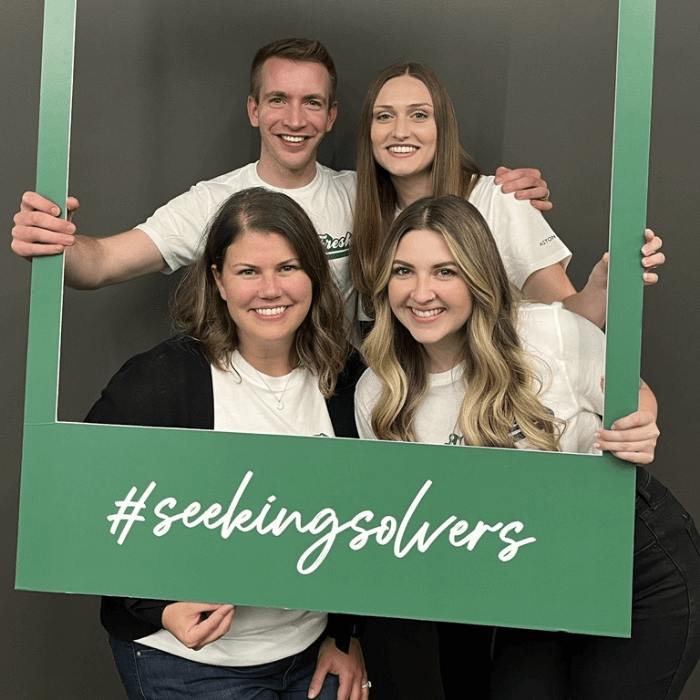 Aston Carter employees smile in a frame that says #seekingsolvers