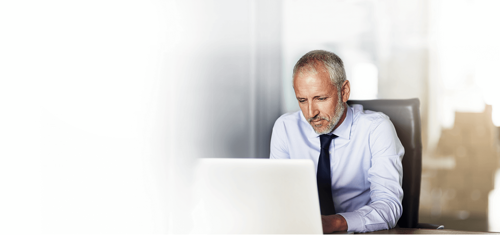 Professional man sitting in a chair and working on his laptop.