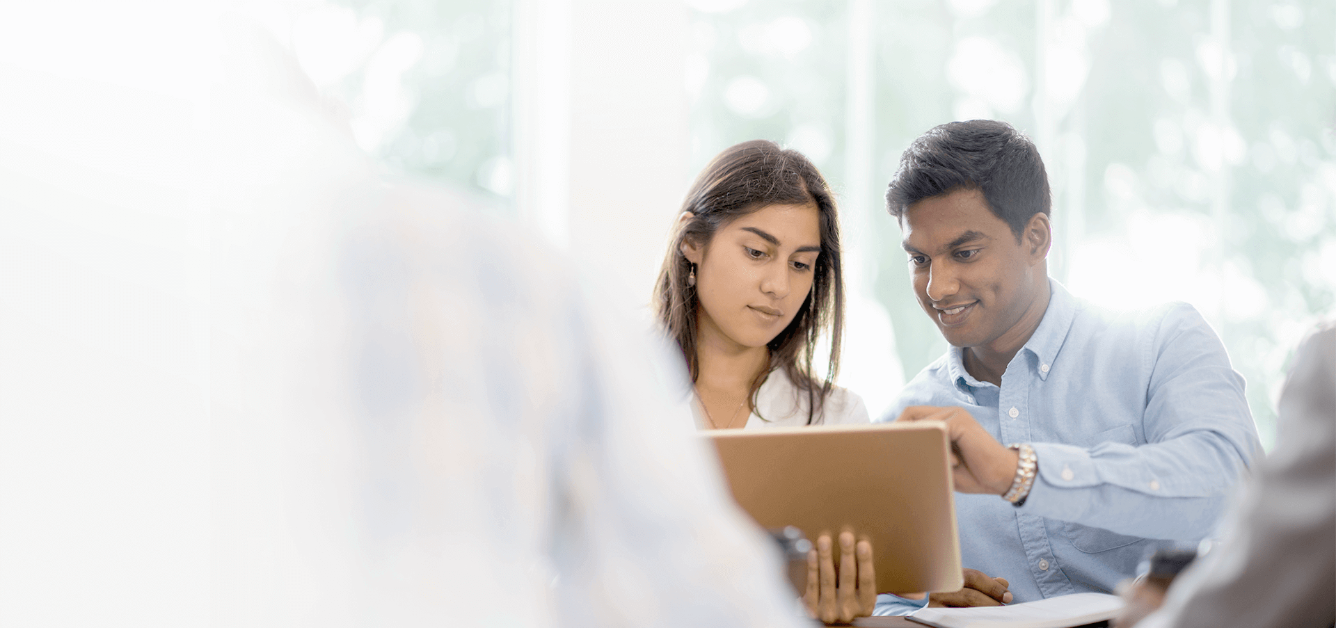 Two professionals sitting and reviewing information on a tablet.