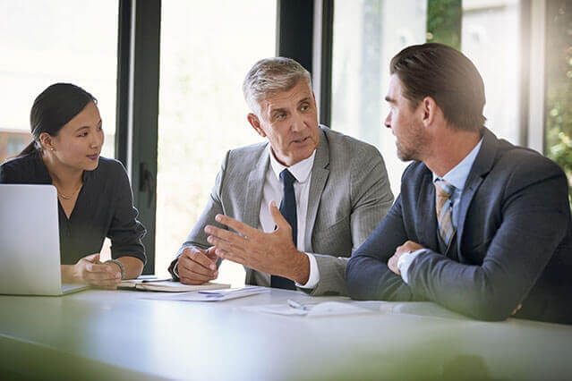 Aston Carter Communications - Four business executives at a desk.