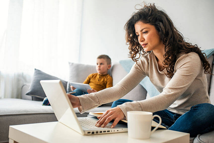 Woman sitting on a couch, opening a laptop.