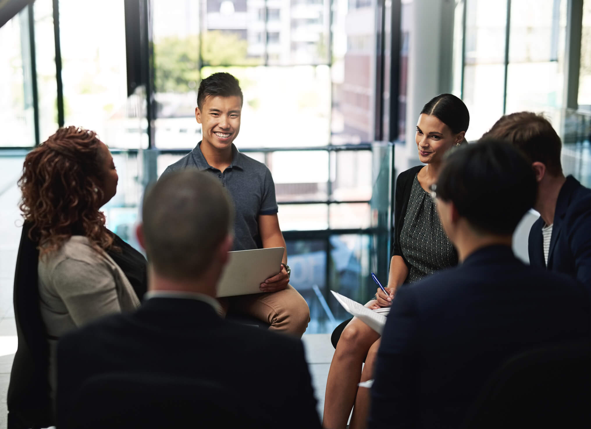 Advantages and Disadvantages A group of colleagues sitting in a circle in the office, conversing during a meeting.