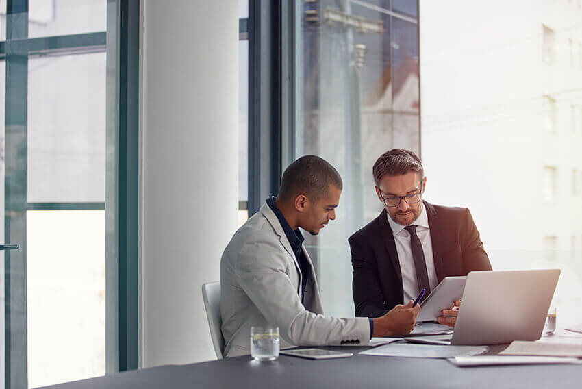 Deux hommes assis ensemble et regardant une tablette.  Articles sur le recrutement d’Aston Carter