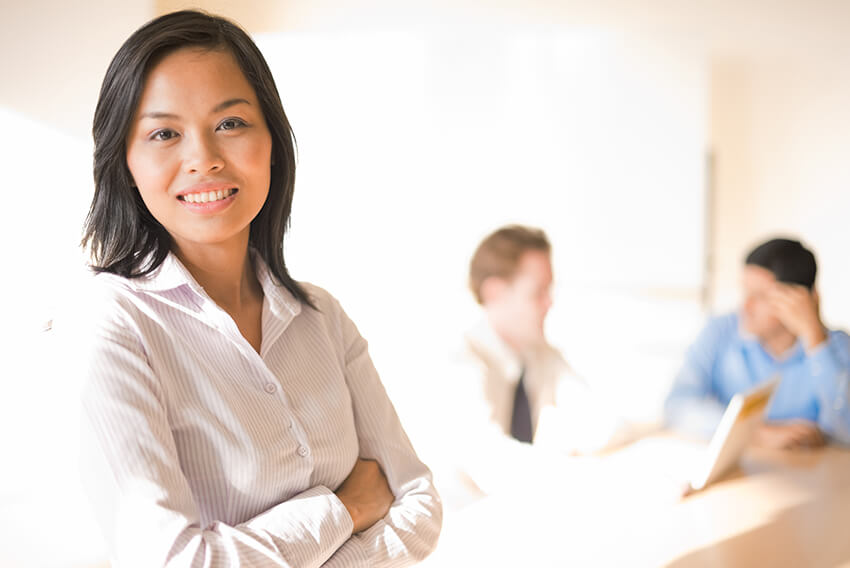 Une femme d’origine asiatique souriante et qui porte une blouse blanche. Articles sur le recrutement d’Aston Carter