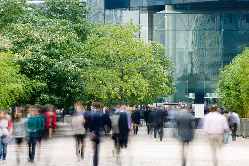 Motion blur view of people walking across a busy street.