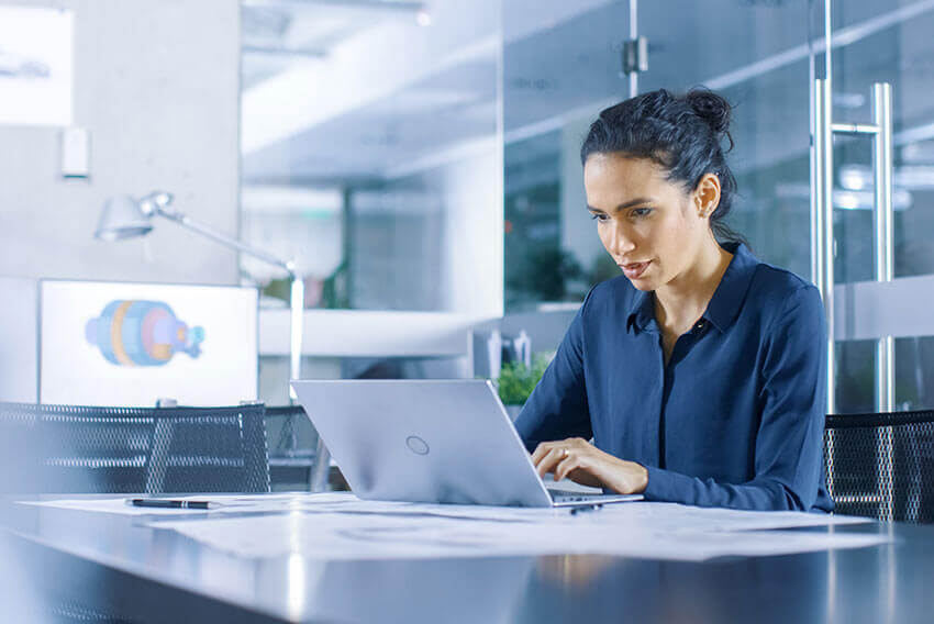 Woman sitting at a table working on a laptop.