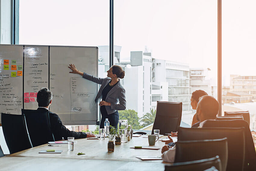 A woman giving a presentation on a white board. Aston Carter Recruitment Articles.