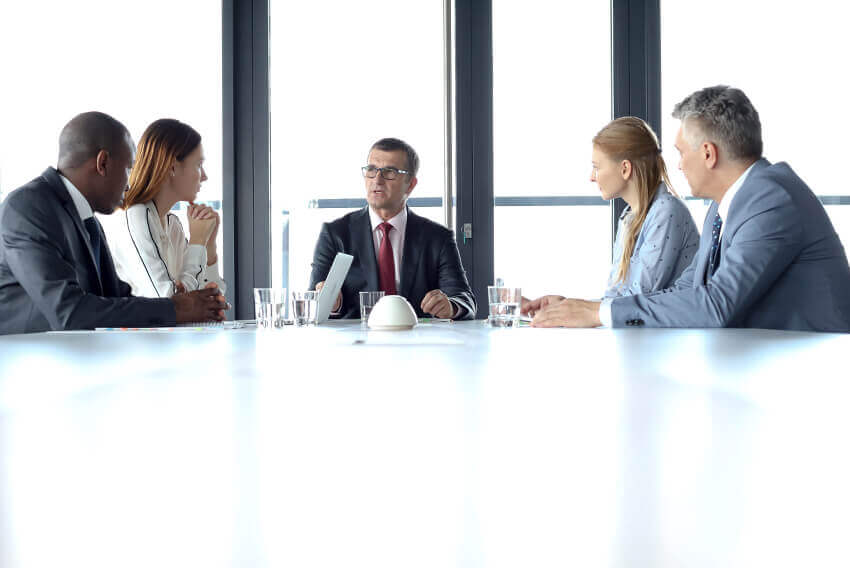  Five people sitting down at a table for a meeting. Aston Carter Recruitment Articles.