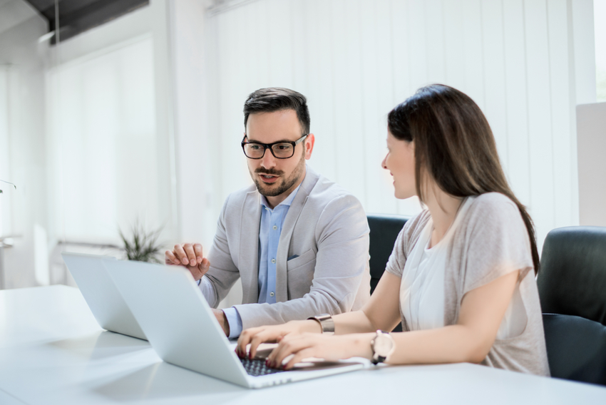 two people working in an office at laptops job searching