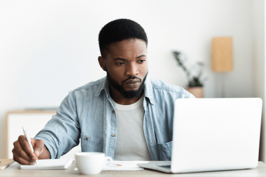 man at laptop writing his CV and holding pen