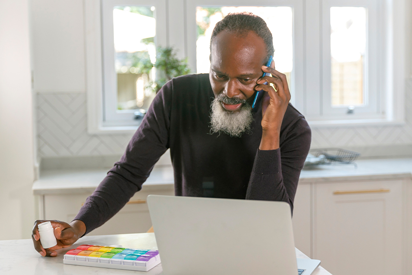 Older man examines medication while on the phone