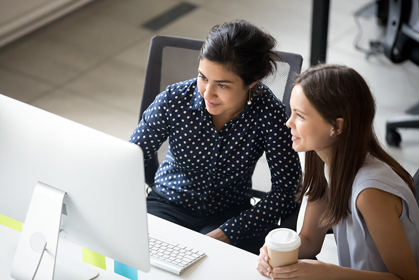 Two women look at a computer monitor together