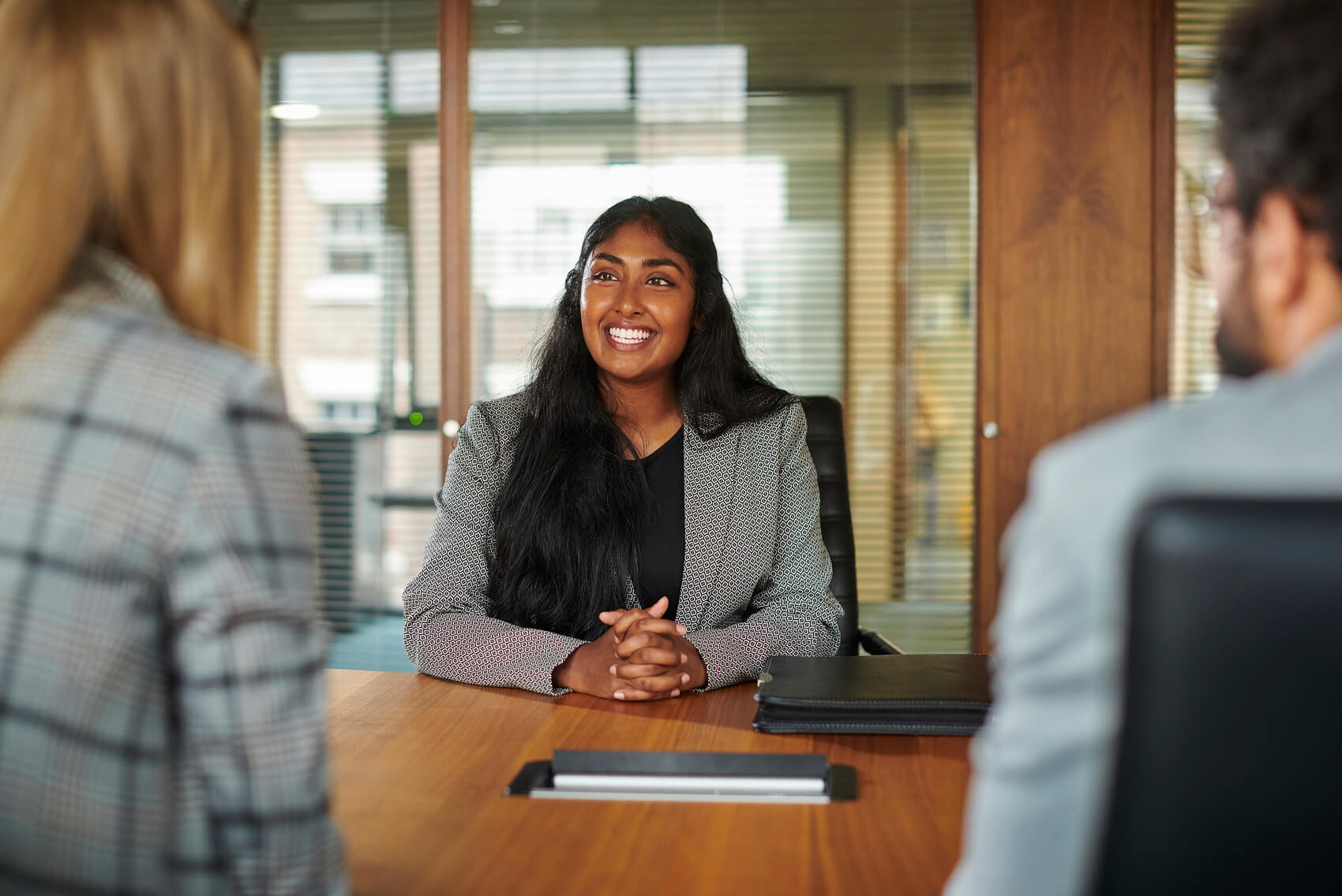 A woman at an in-person interview discussing different types of interviews with two professionals.