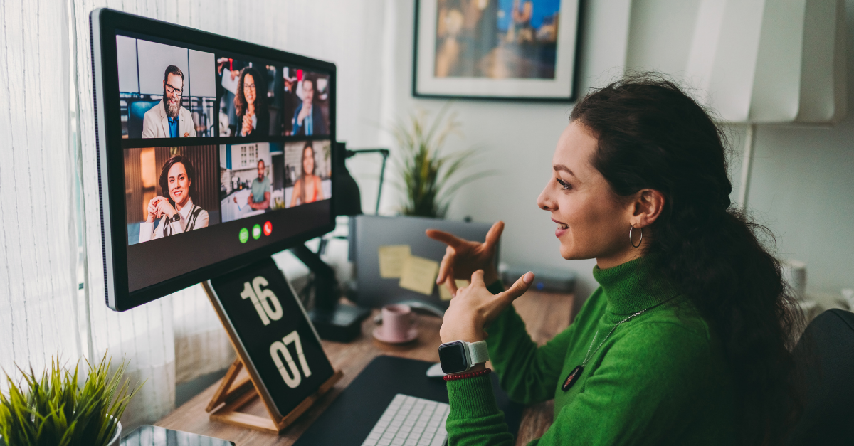 Female employee smiling and talking to coworkers on a virtual business meeting. 