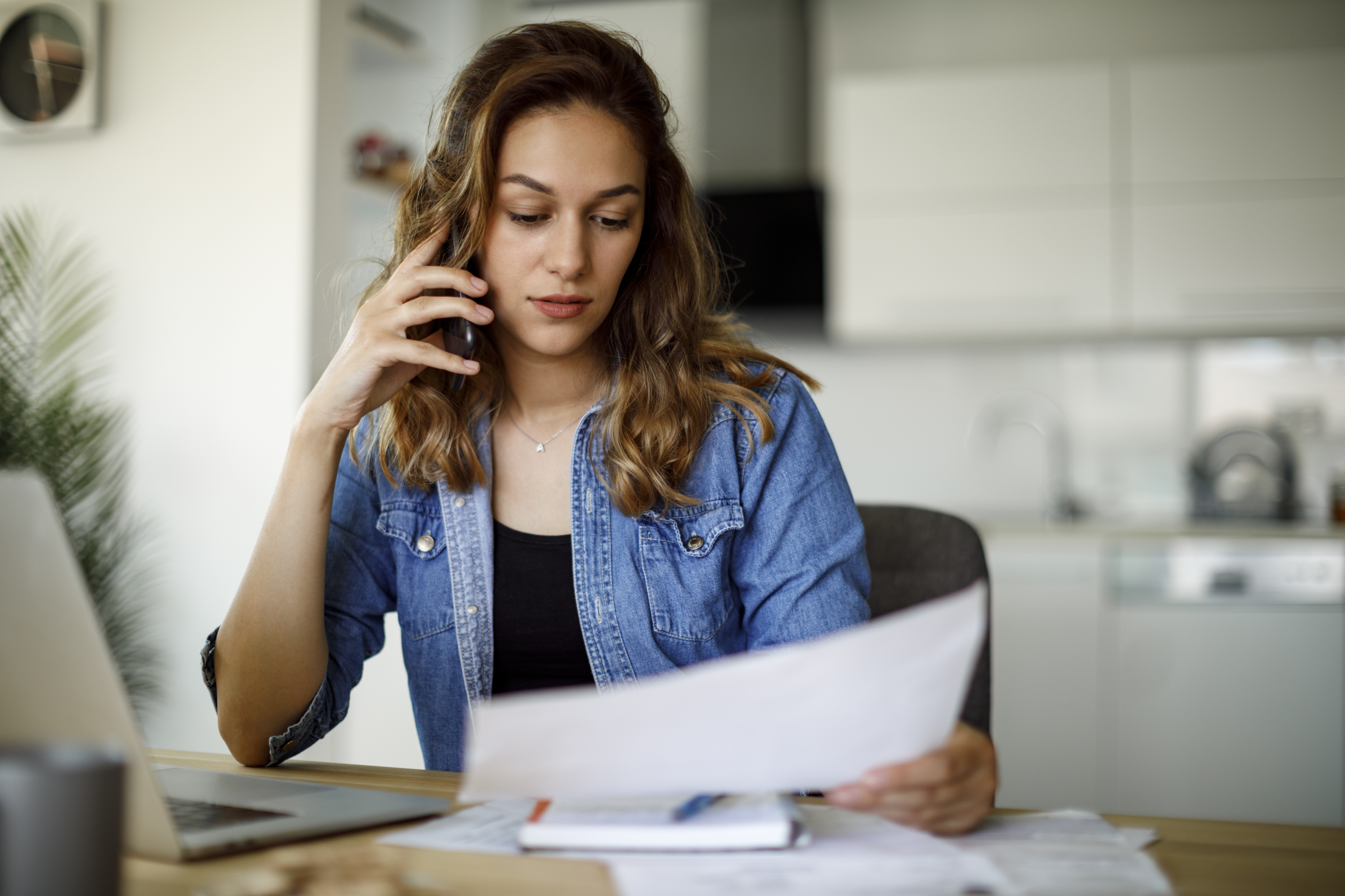 Woman sits at her desk looking at a piece of paper