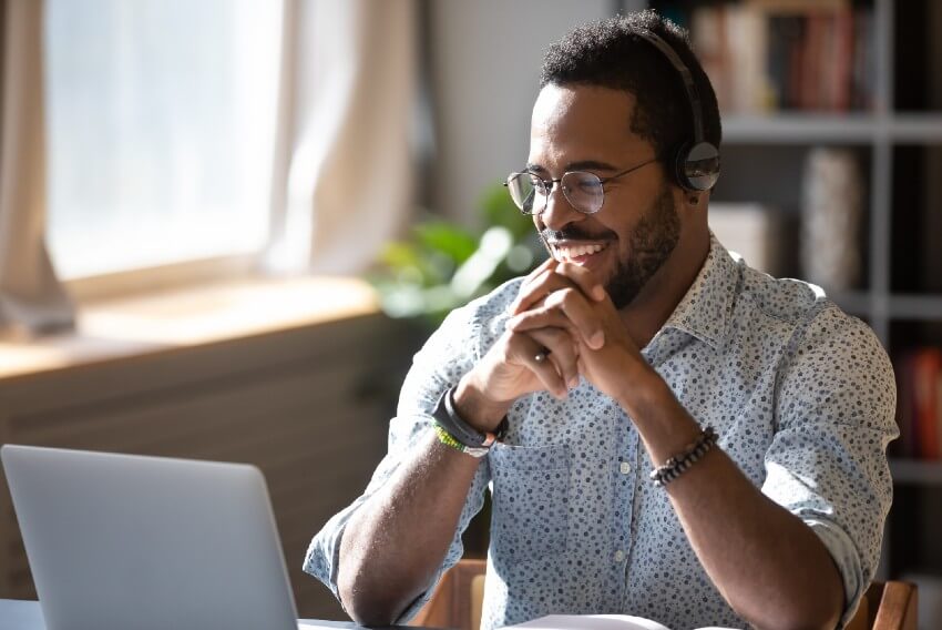 man smiling at laptop screen on a virtual meeting