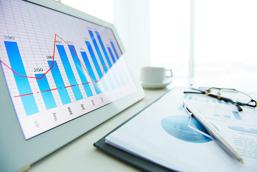 A tablet displaying a graph image, cup of coffee and paper files. Aston Carter Recruitment Articles.