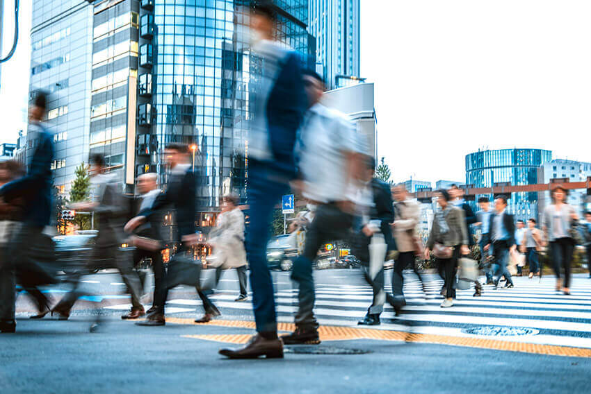 Motion blur focus of professionals walking across a busy intersection.