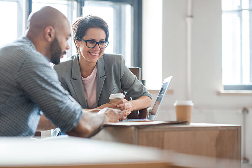 Woman and man working together in front of a laptop.  Aston Carter Recruitment Articles.