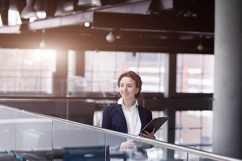 Woman holding a laptop, walking in an office. Aston Carter Recruitment Articles.