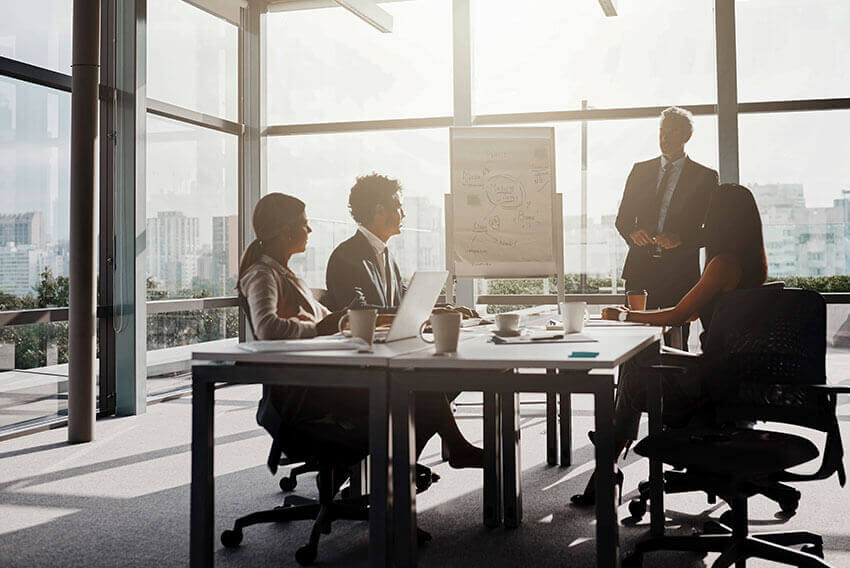 4 professionals in a conference room, talking and collaborating.