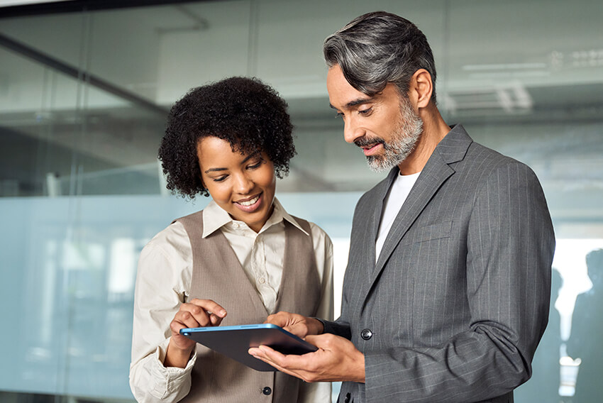 Male and female professionals reviewing the January 2026 jobs report on an iPad looking at December 2025 labor market and economy trends.