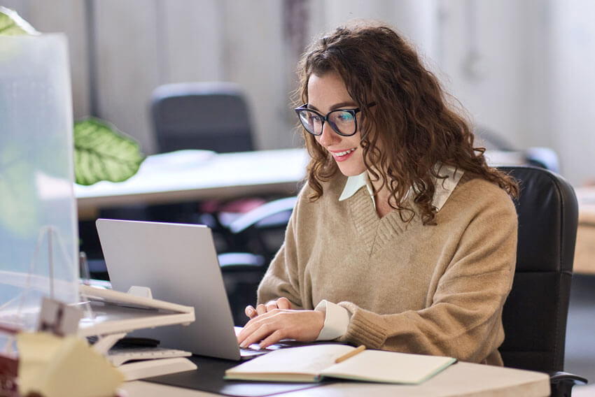 A female reading the May 2024 jobs report on her laptop and analyzing April's labor market and economy trends.