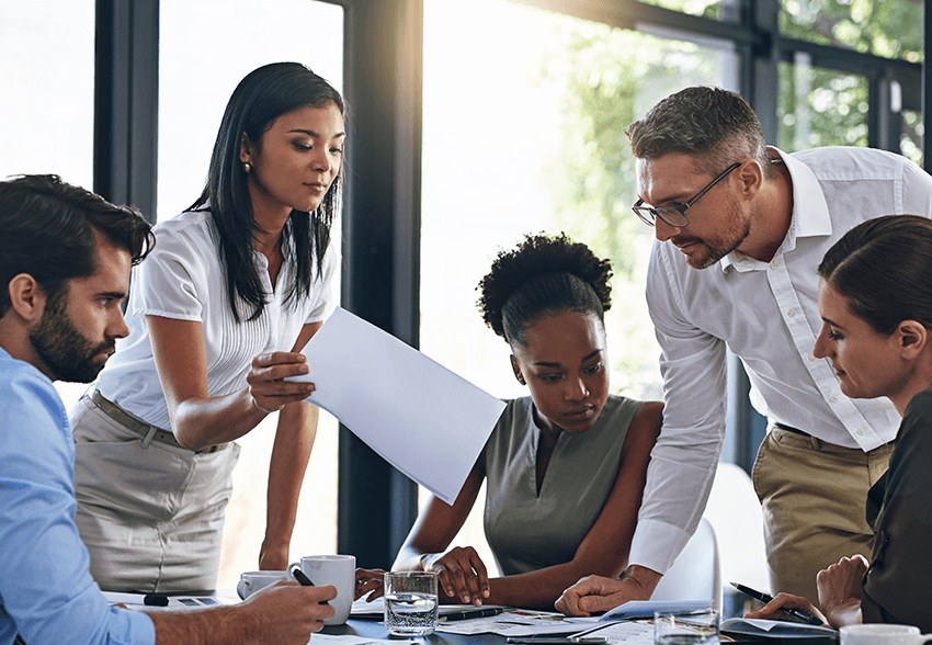 A diverse group of business people look at a file together