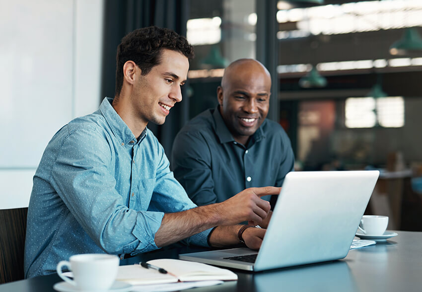 Two men collaborate over a laptop