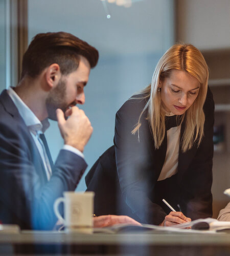 Male and female cowokers reviewing recent tariff impacts on accounting and finance professionals.
