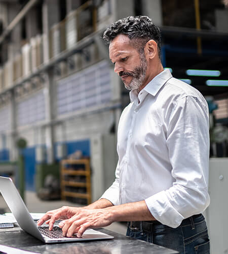 A male professional researching on his laptop about the tariffs increased demand for specialized skills.