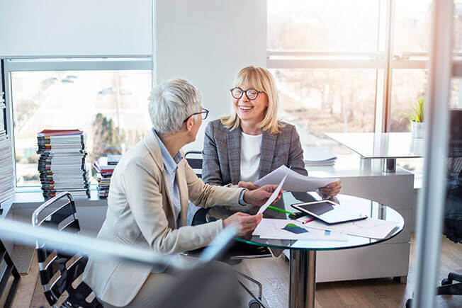 Aston Carter Careers Business Disciplines Business Support. Two women discussing business at a table. 