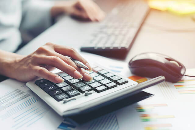 Person at computer desk using a calculator
