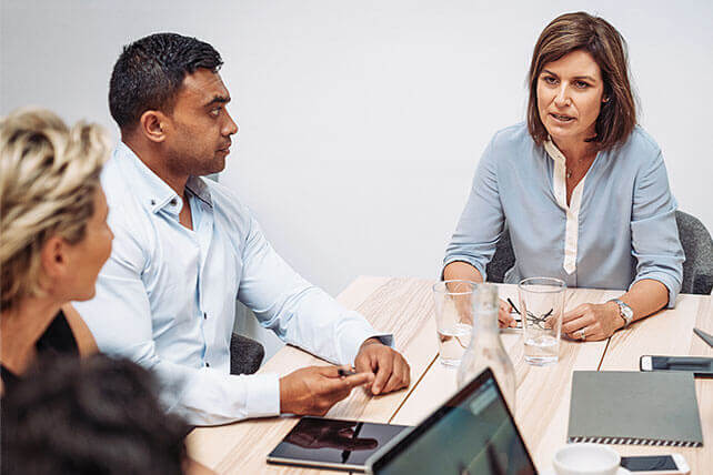 Aston Carter Careers Business Disciplines Communications. A woman and a man deliberating a decision as another woman looks on.