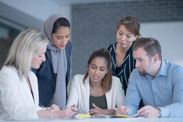 Aston Carter Corporate Responsiblity. A diverse set of 5 business people discussing a document. 